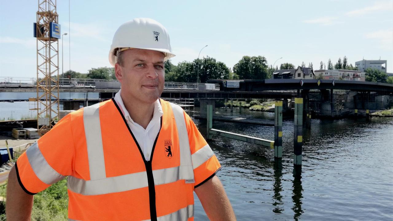 Arne Huhn, Senatsverwaltung für Verkehr, mit Helm und Warnweste vor der Baustelle der Salvador-Allende-Brücke.