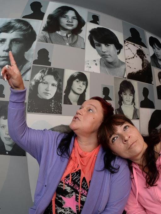 In einem Raum mit Porträtfotos sitzen Jana Mendes Bogas (l) und Ilona Dothe am 14.09.2013 auf einem Treffen ehemaliger DDR-Heimkinder in der "Gedenkstätte Geschlossener Jugendwerkhof" in Torgau (Sachsen).