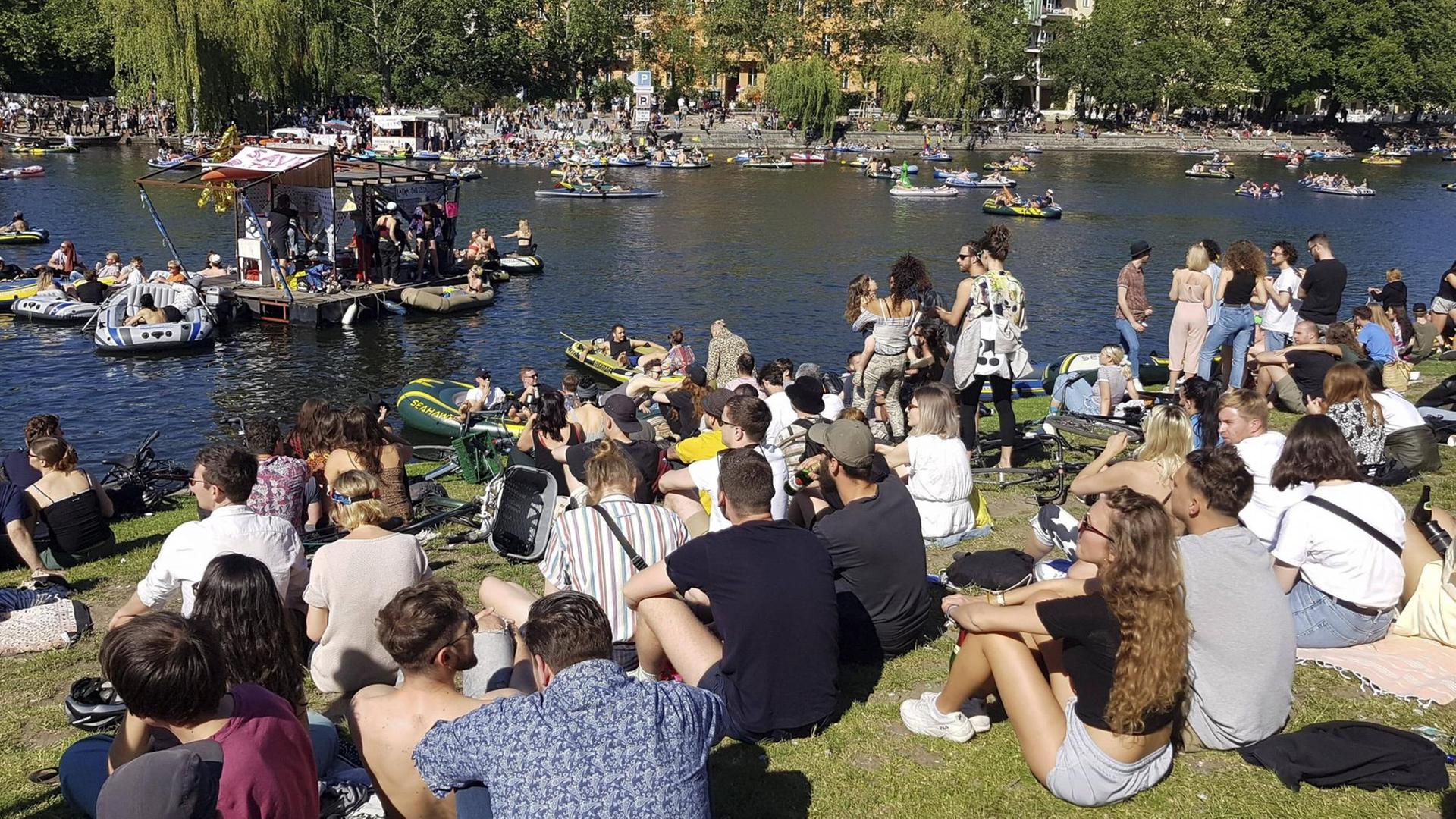 Eine große Menge junger Leute Pfingsten 2020 am Ufer des Berliner Landwehrkanals. Sie sitzen dicht an dicht auf dem Rasen und demonstrieren für Partykultur und Ravekultur.