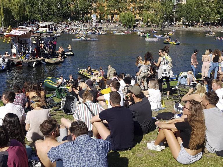 Eine große Menge junger Leute Pfingsten 2020 am Ufer des Berliner Landwehrkanals. Sie sitzen dicht an dicht auf dem Rasen und demonstrieren für Partykultur und Ravekultur.