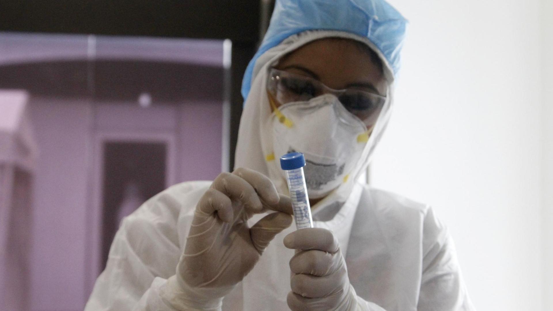 Biologin mit Schutzkleidung bei einem COVID-19-Test im Labor