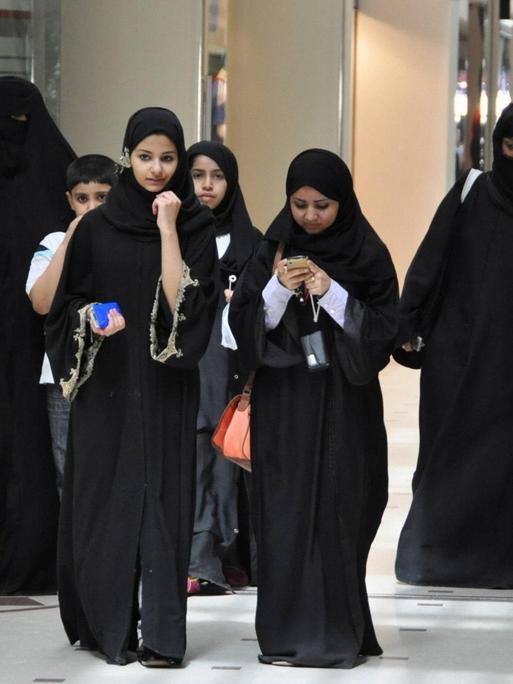 Eine Gruppe von jungen Frauen, gekleidet in den traditionellen schwarzen Umhang, die Abaya, geht durch eine Shopping Mall in der saudi-arabischen Hauptstadt Riad.