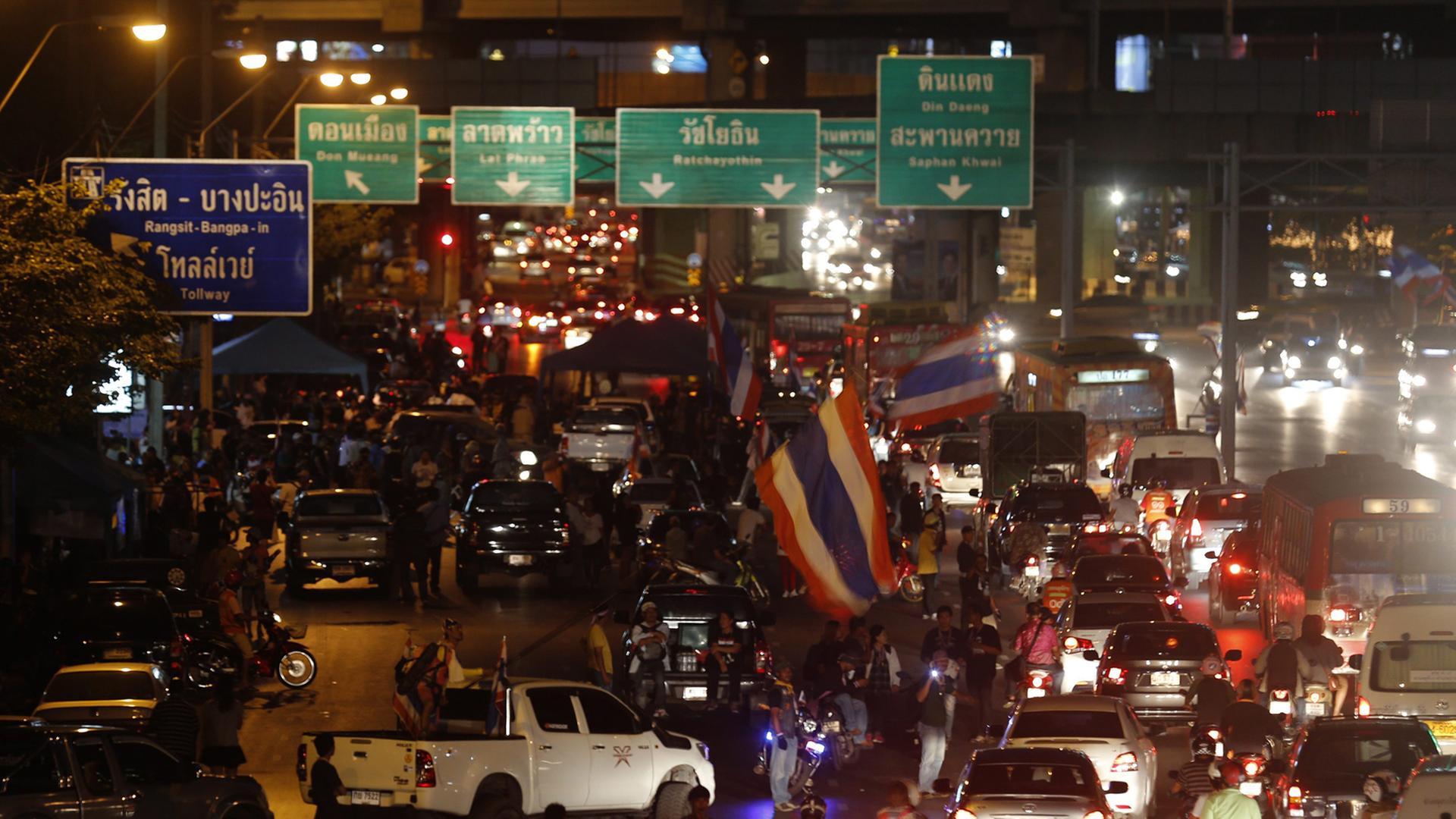 Eine Hauptverkehrsstraße in Bangkok am Abend, auf der sich lange Autoschlangen bilden