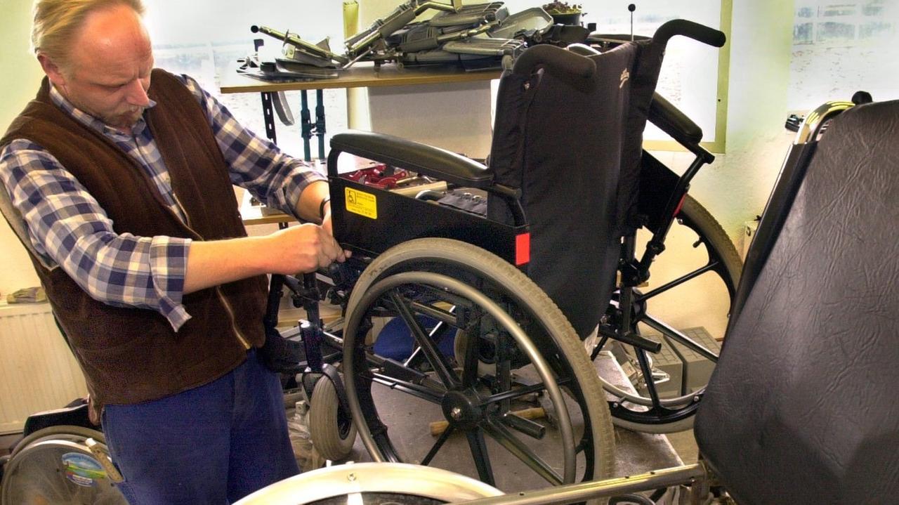 Ein Mitarbeiter der Werkstatt für gebrauchte medizintechnische Geräte des Vereins Start e.V. in Schwerin repariert am einen Rollstuhl.