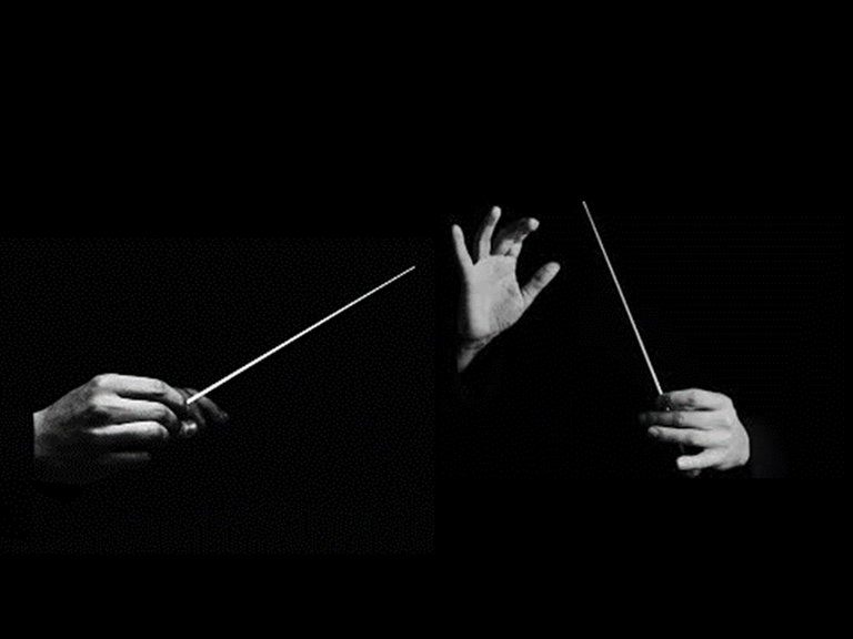 Auf einem s/w-Bild sind zwei Paar Hände vor schwarzem Hintergrund zu sehen, die jeweils einen Taktstock halten.