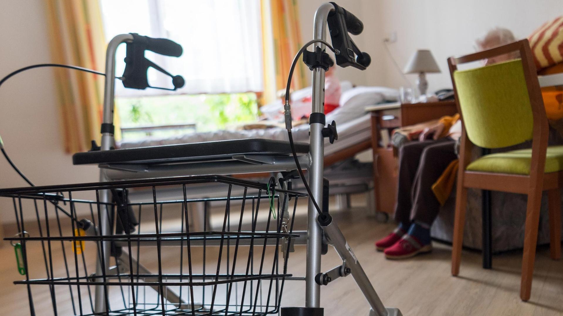 Ein Rollator steht im Zimmer einer älteren Frau.