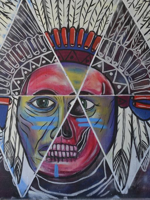 Ein buntes Graffiti zeigt einen Indianer mit großem Federschmuck.