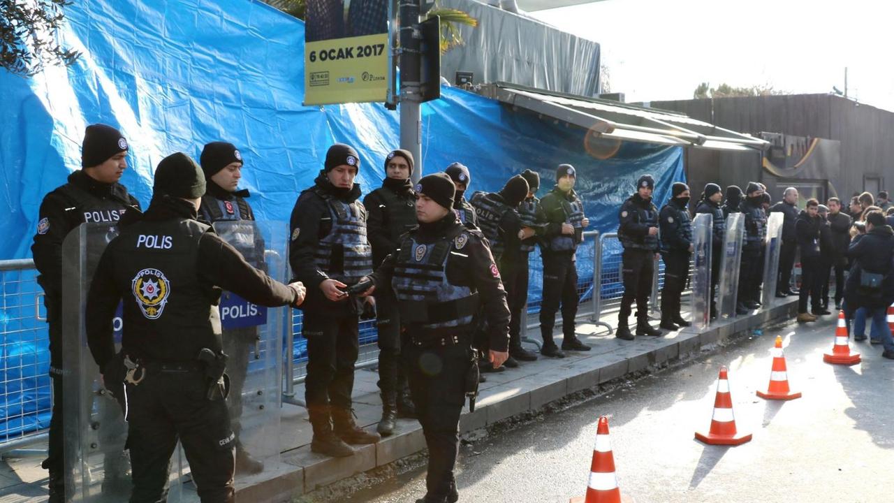 Die Polizisten stehen in einer Reihe auf dem Bürgersteig vor dem mit einer blauen Plane verdeckten Eingang zum Club.