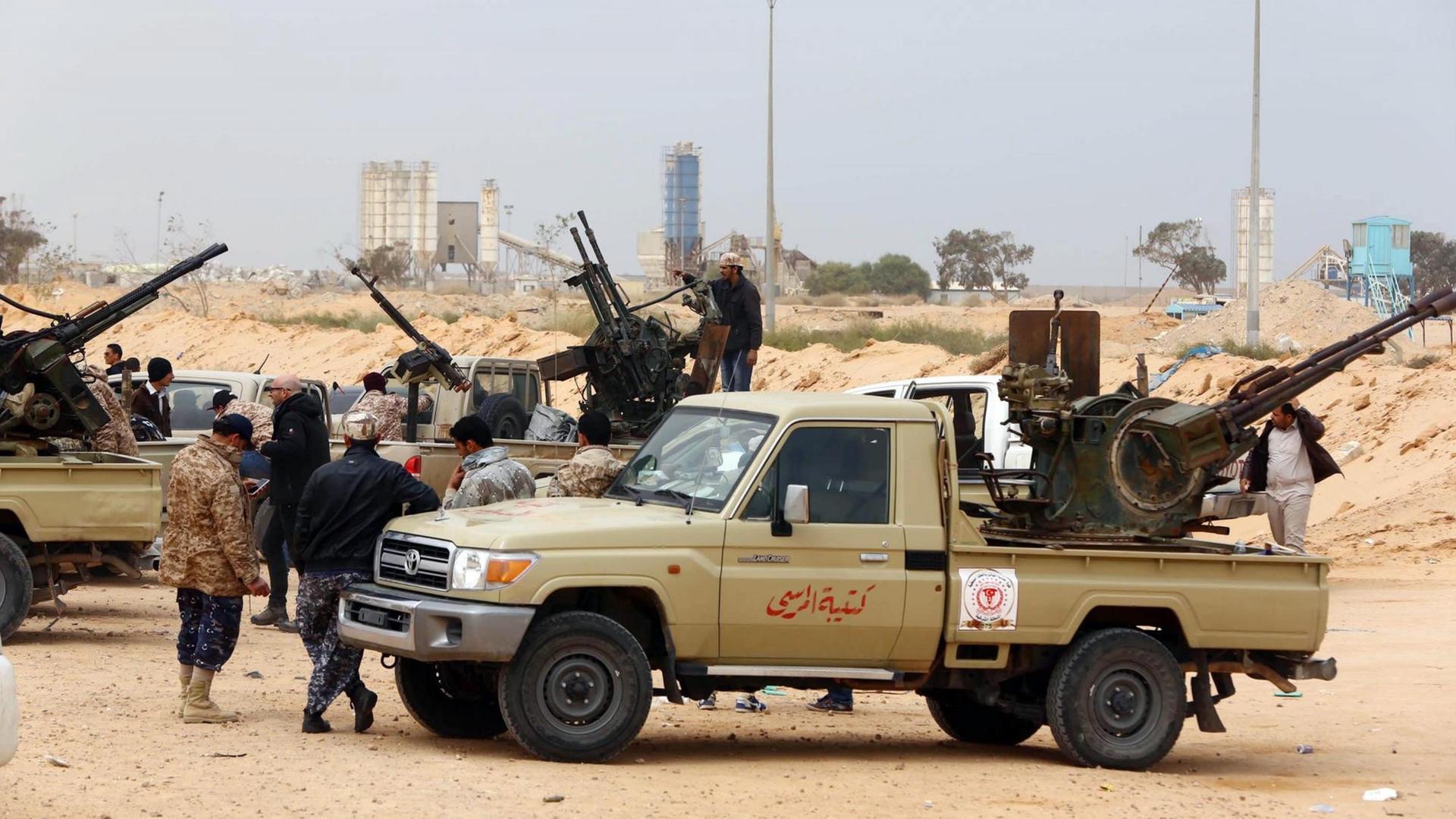 Kämpfer sitzen in der Nähe von Sirte auf Autos, die mit Waffen beladen sind.