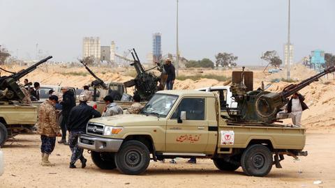 Kämpfer sitzen in der Nähe von Sirte auf Autos, die mit Waffen beladen sind.