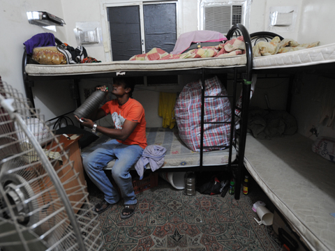 Ein Wanderarbeiter sitzt auf einem Etagenbett in seiner Unterkunft in Katar.