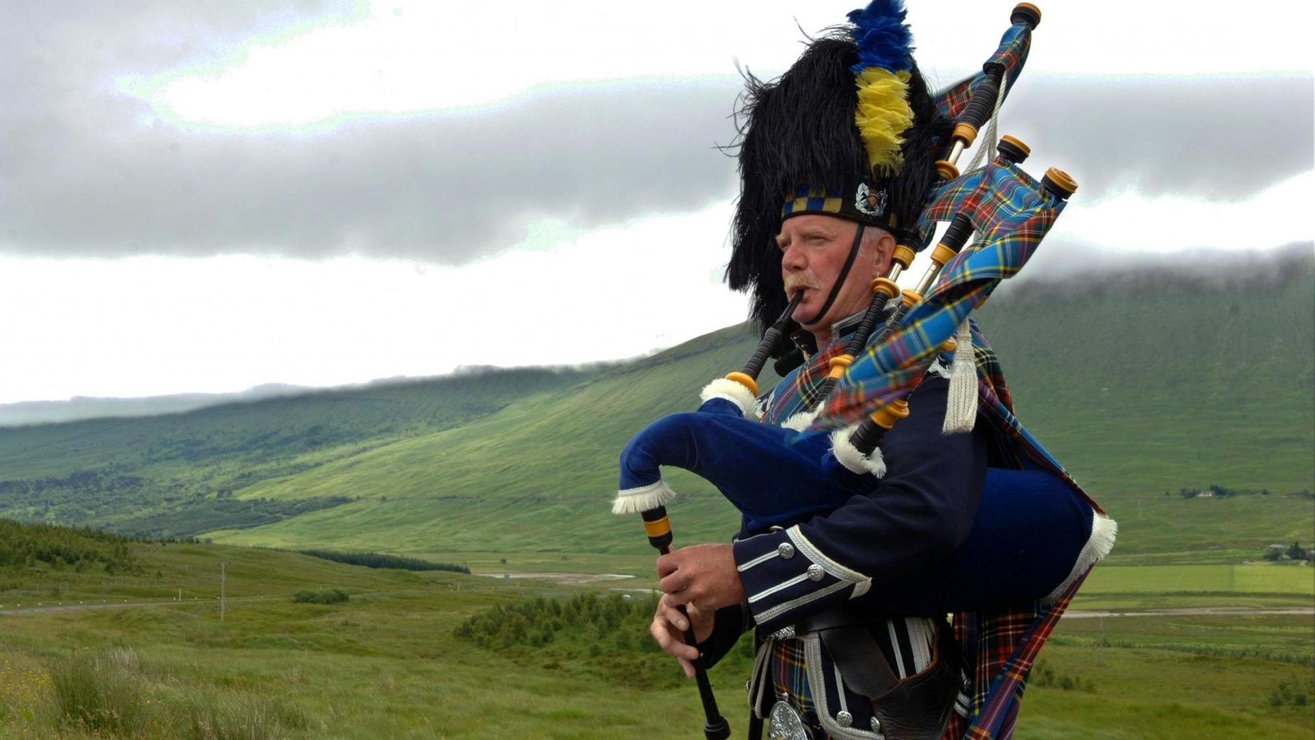 Ein Dudelsackspieler in den Farben des Clans MacBeth spielt im Hochland bei Glen Coe in Schottland für die Touristen, aufgenommen am 09.07.2005.