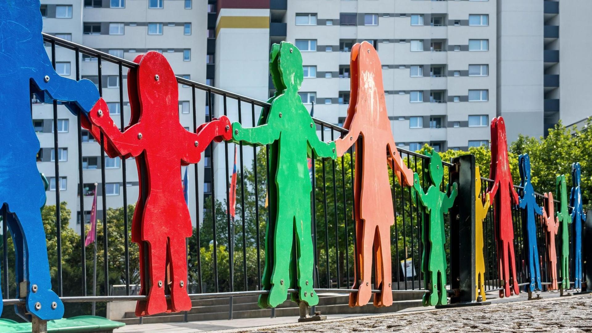 Bunte Silhouetten von Kinderfiguren an einem Kinderspielplatz.