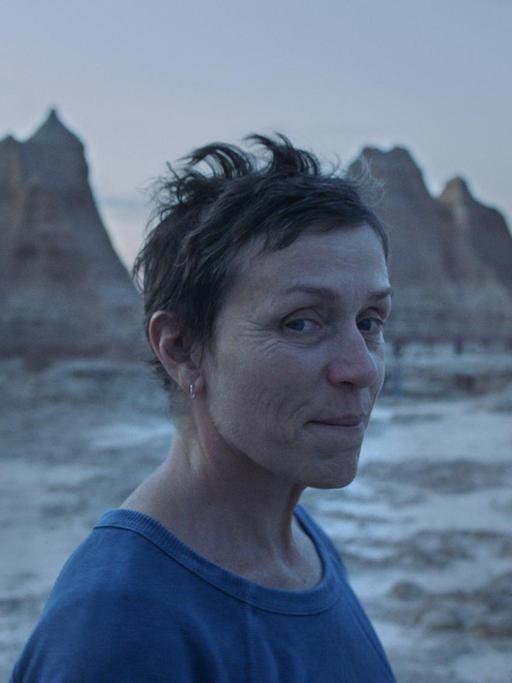 Frances McDormand vor Felsenlandschaft, lächelt in die Kamera