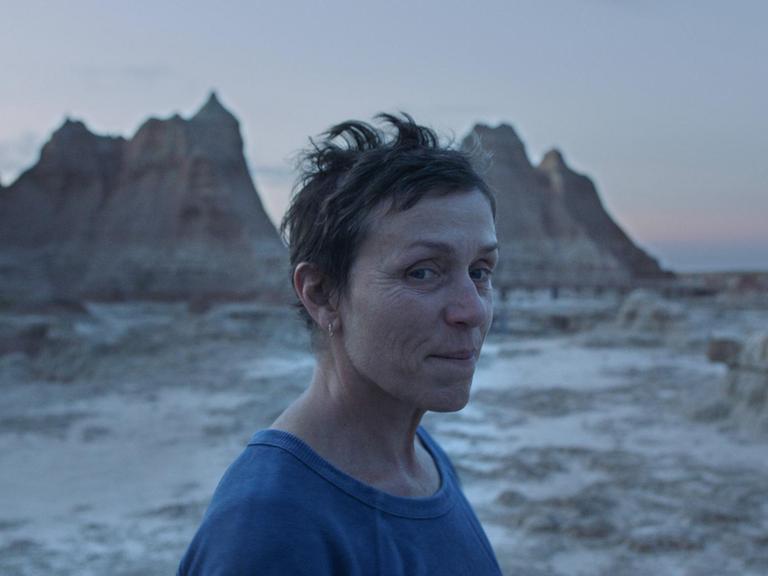 Frances McDormand vor Felsenlandschaft, lächelt in die Kamera