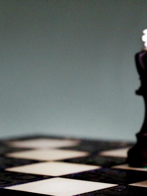 Auf einem Schachbrett steht die Spielfigur der Königin im Vordergrund.
