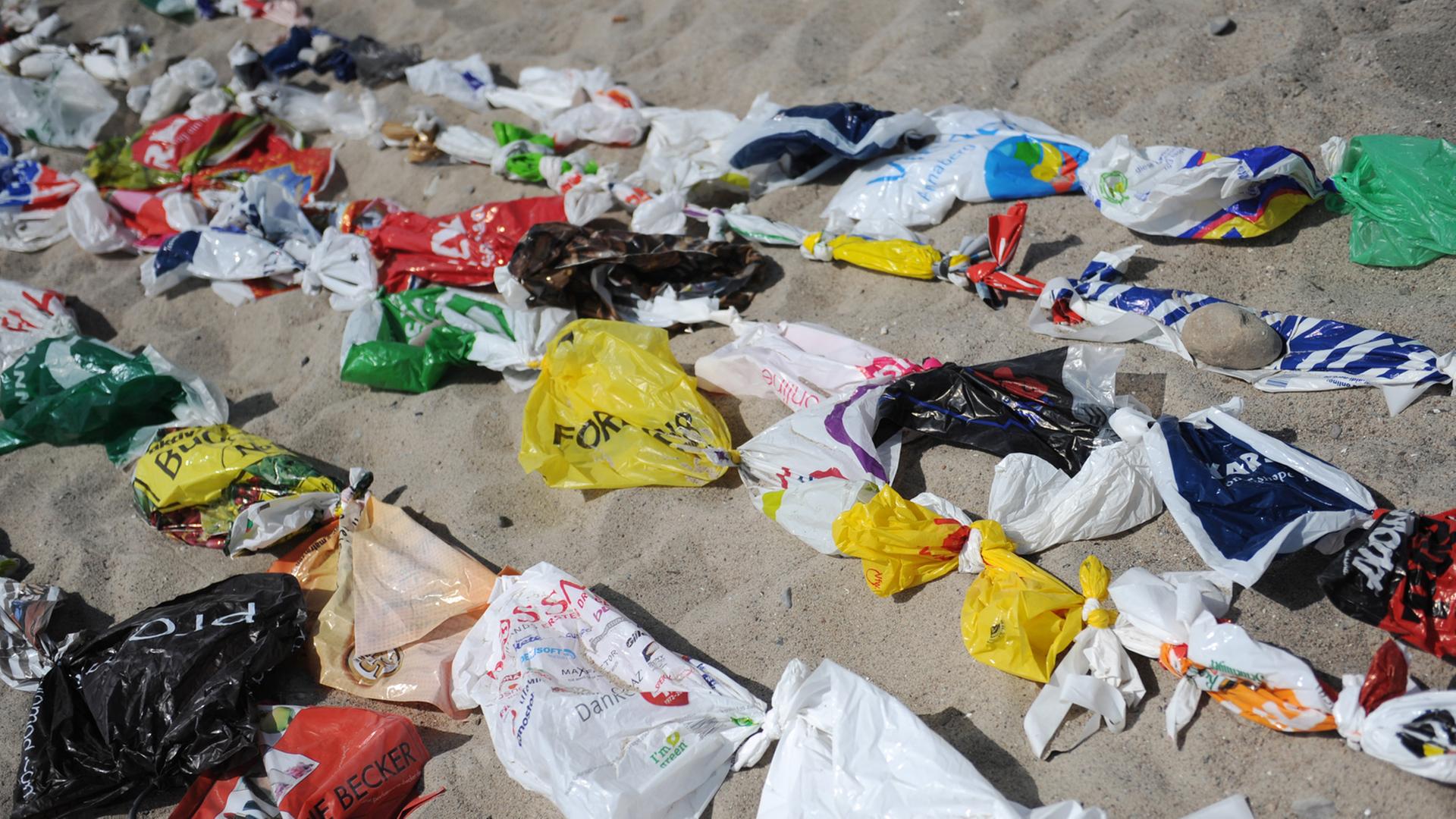 Angeschwemmter Plastikmüll liegt an einem Strand