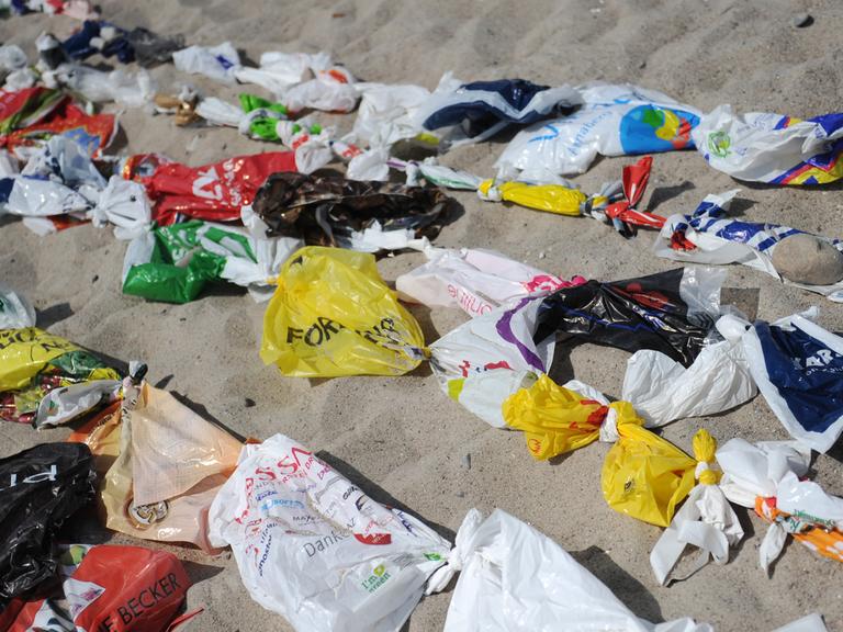 Angeschwemmter Plastikmüll liegt an einem Strand