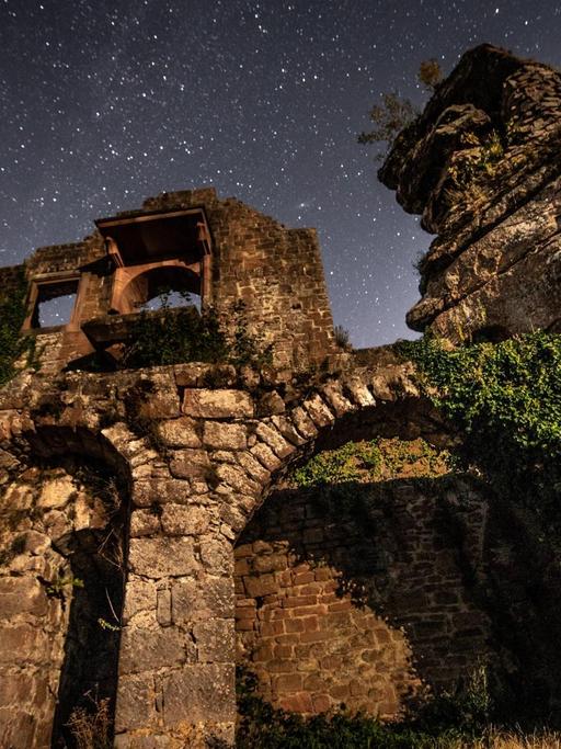 Blick von unten auf eine Ruine mit Sternenhimmel