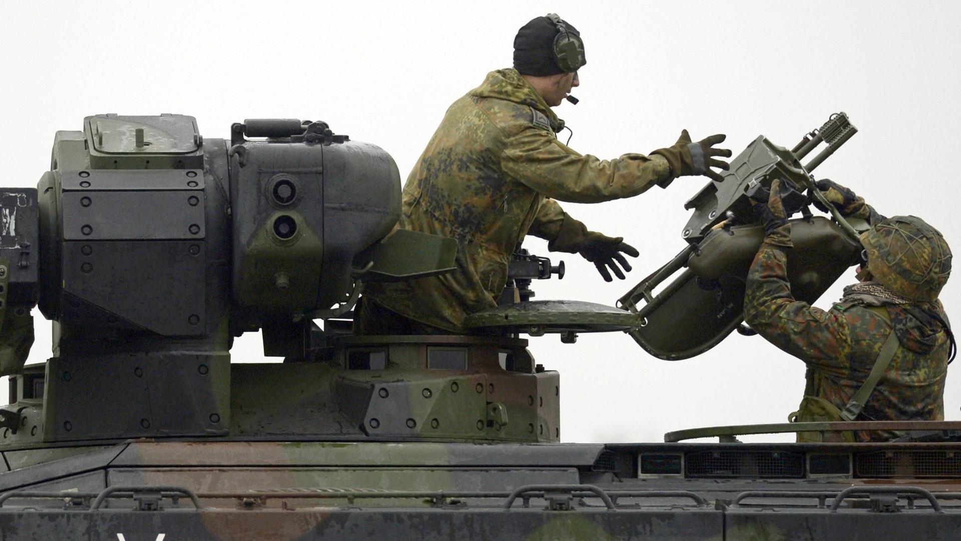 Zu sehen ist ein Panzer mit zwei Soldaten und Teilen für einen Raketen-Werfer.