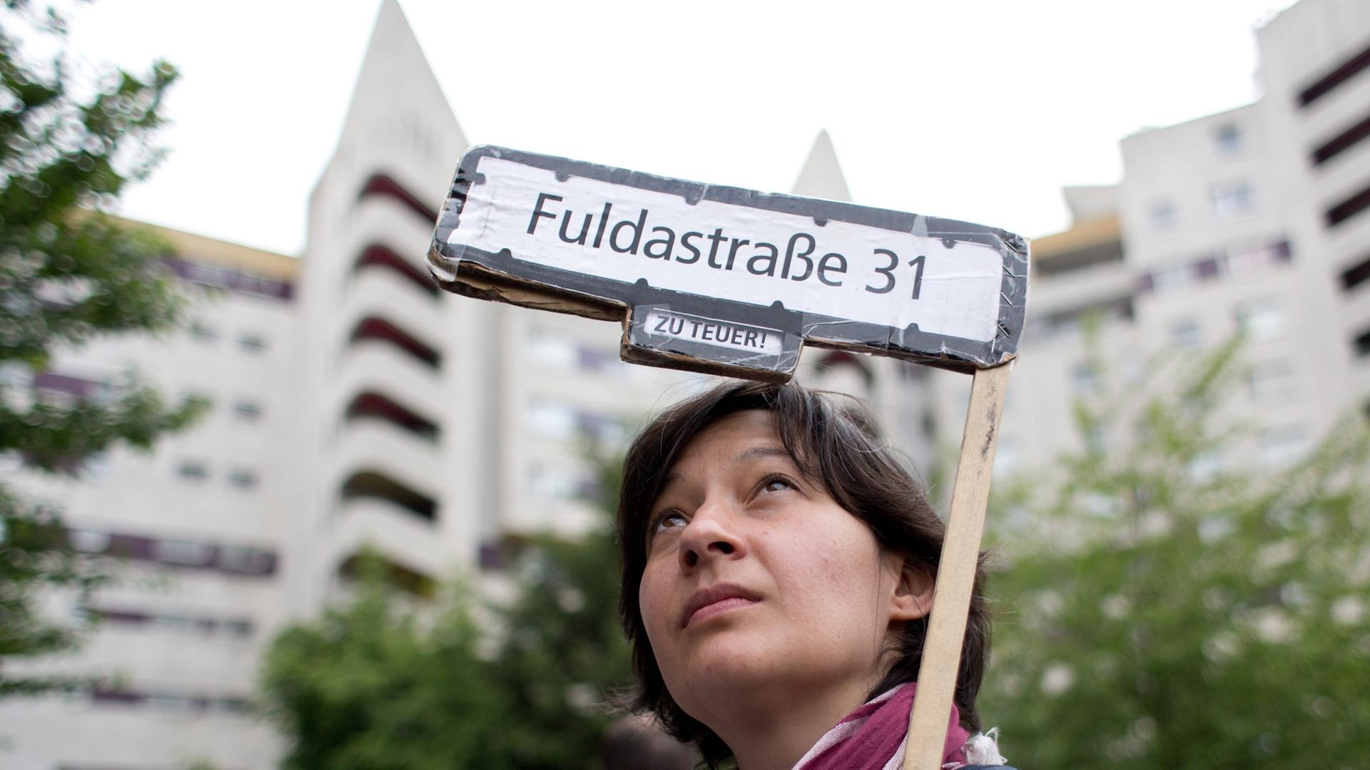 Eine Aktivistin hält ein Transparent hoch mit der Aufschrift "Fuldastraße 31 - zu teuer!" bei einer Demonstration gegen hohe Mieten und Verdrängung in Berlin.
