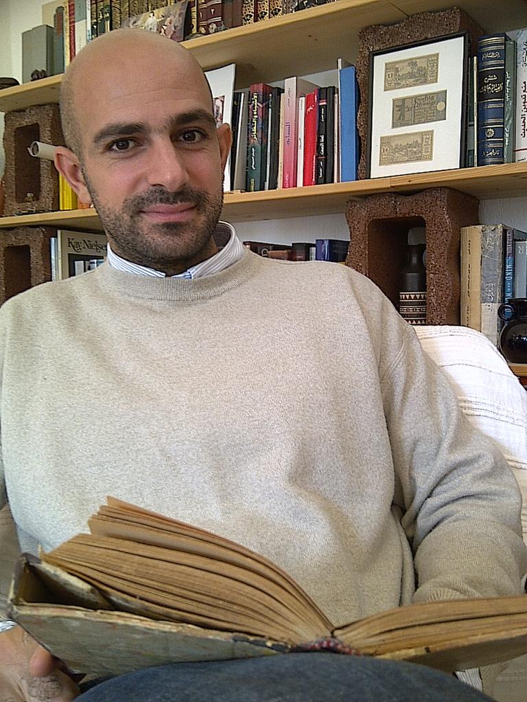 Ghassan El Masri vor einem Bücherregal mit arabischen Titeln. 