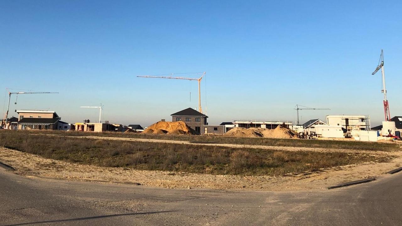 Eine Baustelle, auf der Neubauten und Kräne stehen. Der Himmel ist blau.