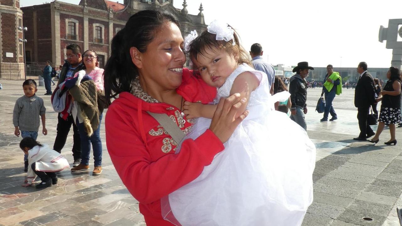 Mutter mit Kleinkind in Tüll vor der Basilika der Jungfrau von Guadalupe.