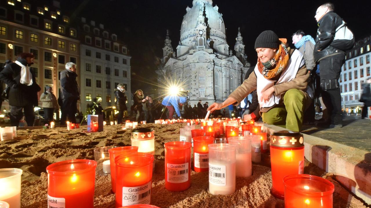 Grablichter und Kerzen brennen während der Gedenkveranstaltung zum 70. Jahrestag der Bombardierung von Dresden. Im Hintergrund die wieder aufgebaute Frauenkirche.