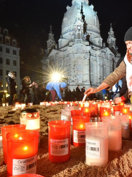 Grablichter und Kerzen brennen während der Gedenkveranstaltung zum 70. Jahrestag der Bombardierung von Dresden. Im Hintergrund die wieder aufgebaute Frauenkirche.
