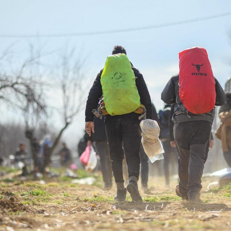 Flüchtlinge sind an einem türkischen Absperrzaun am Grenzübergang Pazarkule-Kastanies in Richtung Griechenland unterwegs. 