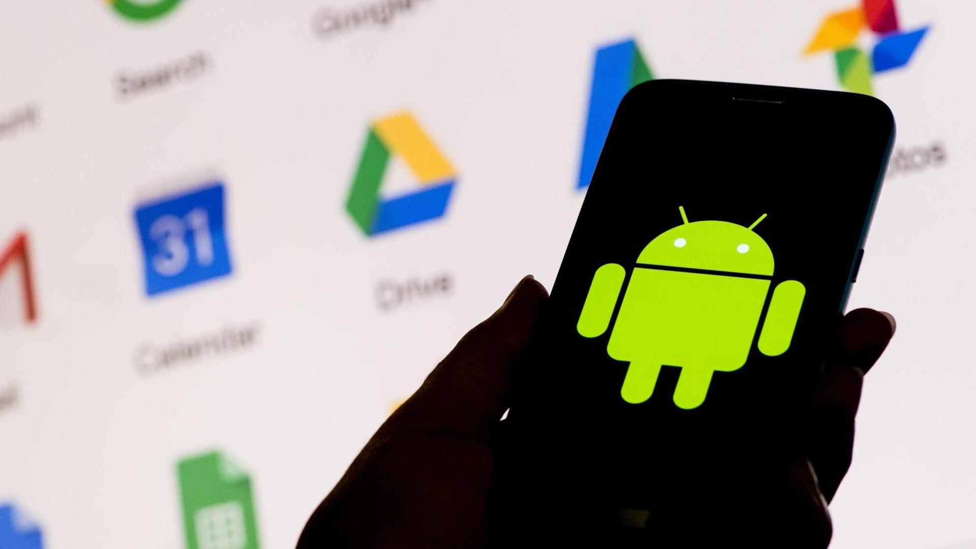 Ein Smartphone zeigt das Android-Logo von Google, dahinter ein Bildschirm