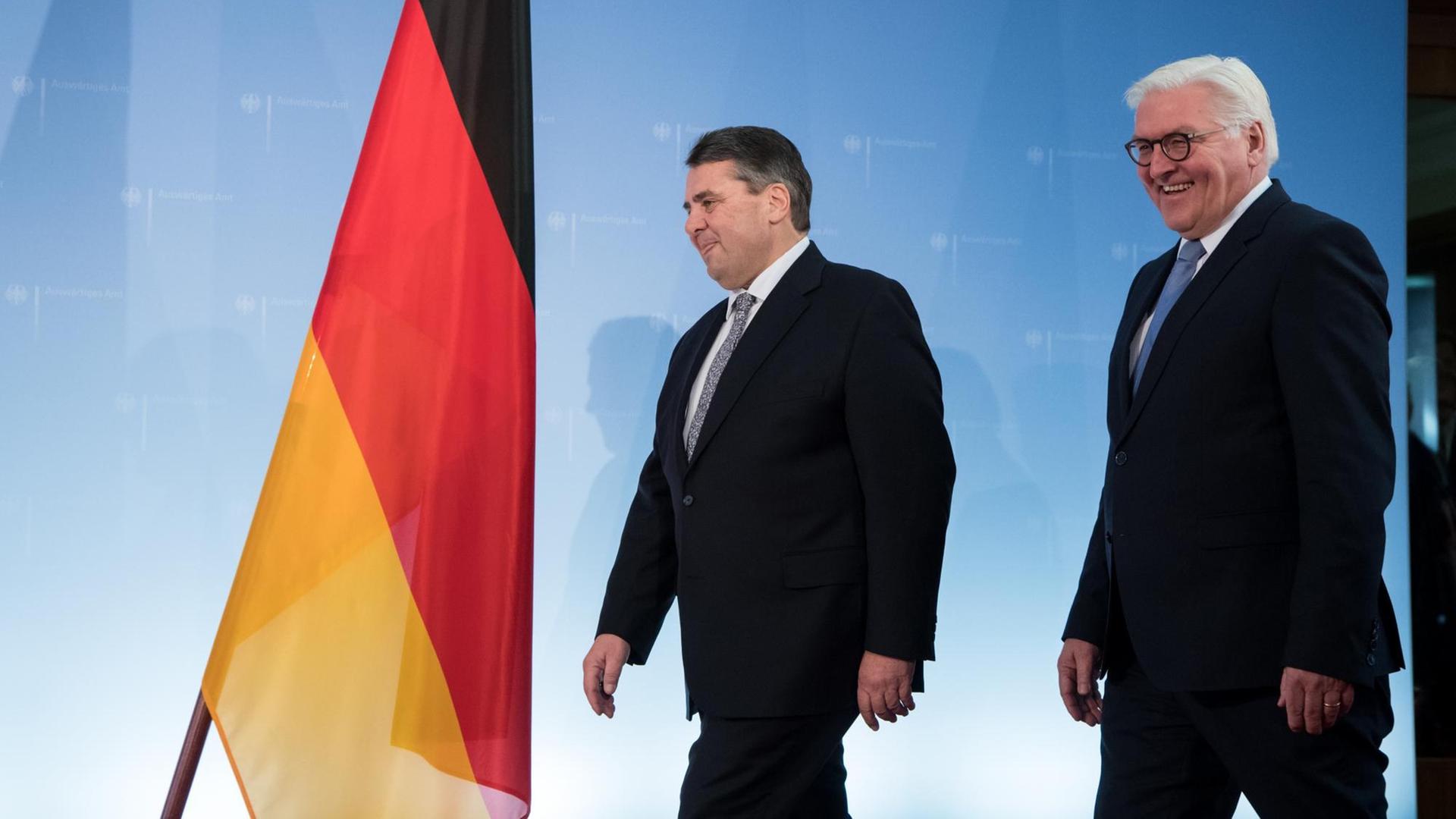 Sigmar Gabriel und Frank-Walter Steinmeier gehen an einer Deutschlandfahne vorbei.