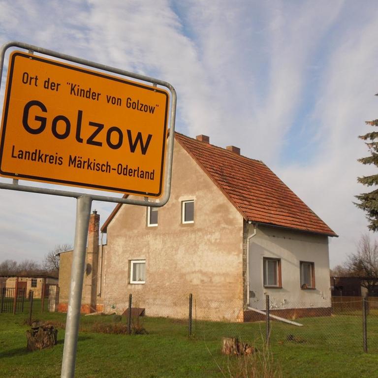 Ortsschild von Golzow, Haus im Hintergrund
