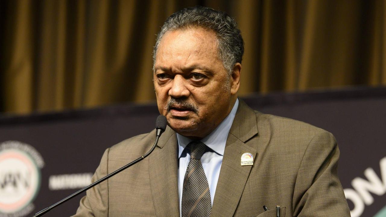 Jesse Jackson steht an einem Rednerpult und spricht in ein Mikrofon.