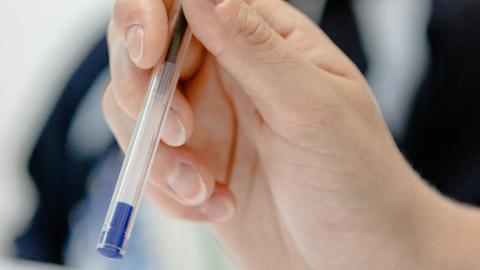 Eine Frau hält einen Stift in der Hand.