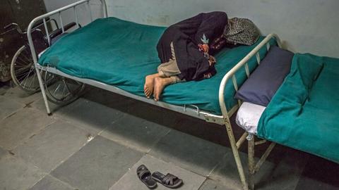 Eine Schizophrenie-Patientin liegt auf einem Bett in einer psychiatrischen Klinik in Indien