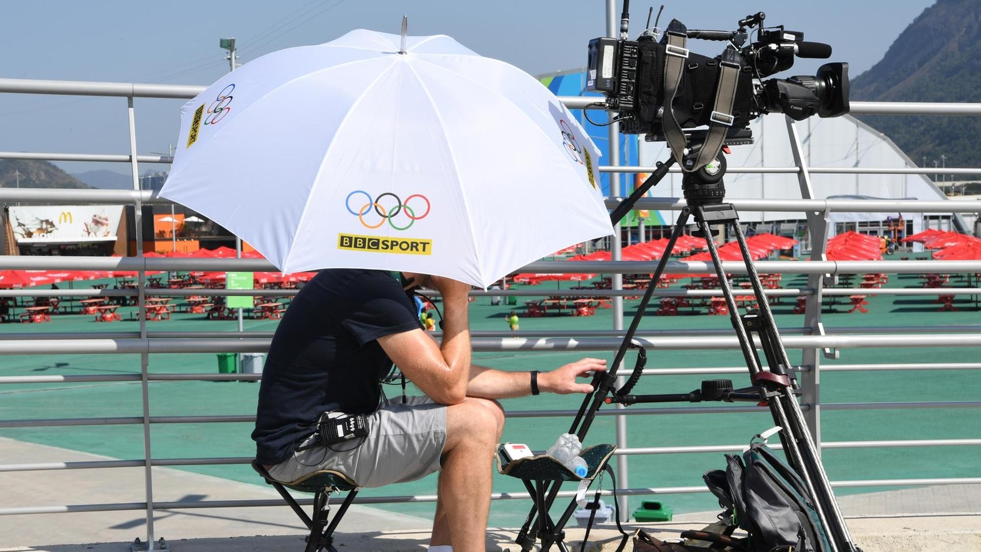 Ein BBC-Kameramann schützt seinen Kopf mit einem Schirm vor der Sonne.