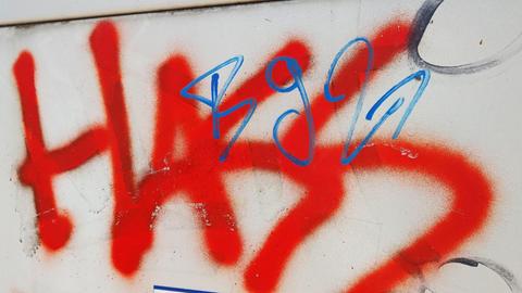 Das Wort "Hass" steht gesprüht in roter Farbe auf einem Stromkasten