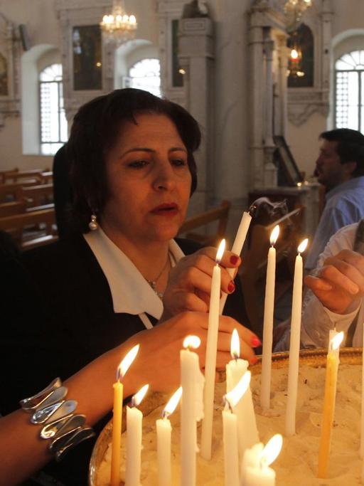 Orthodoxe Christen entzünden in einer Kirche in Damaskus, Syrien, Kerzen.