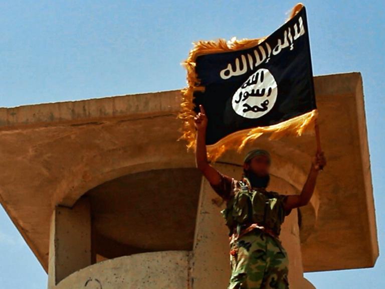 Ein Anhänger des IS mit der Flagge der Miliz