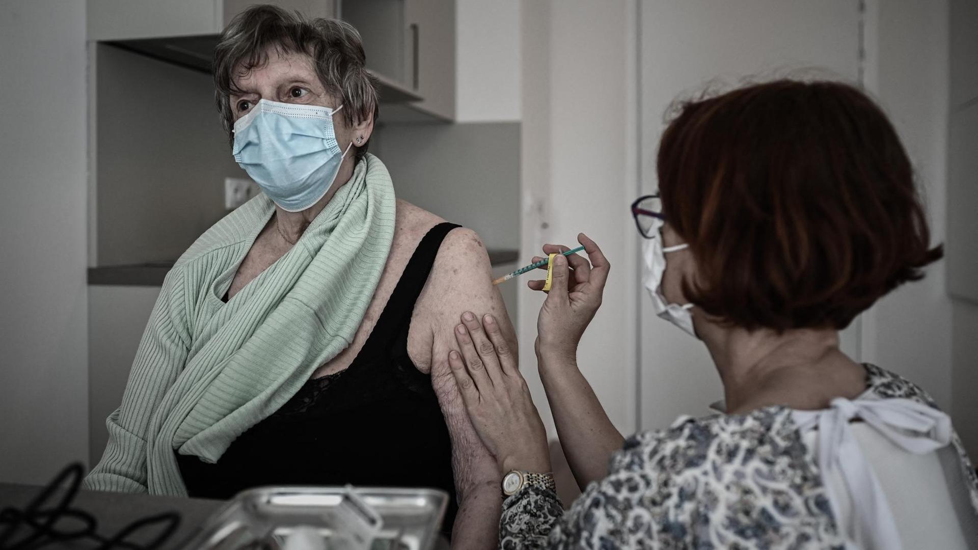 Eine französische Seniorin wird geimpft.