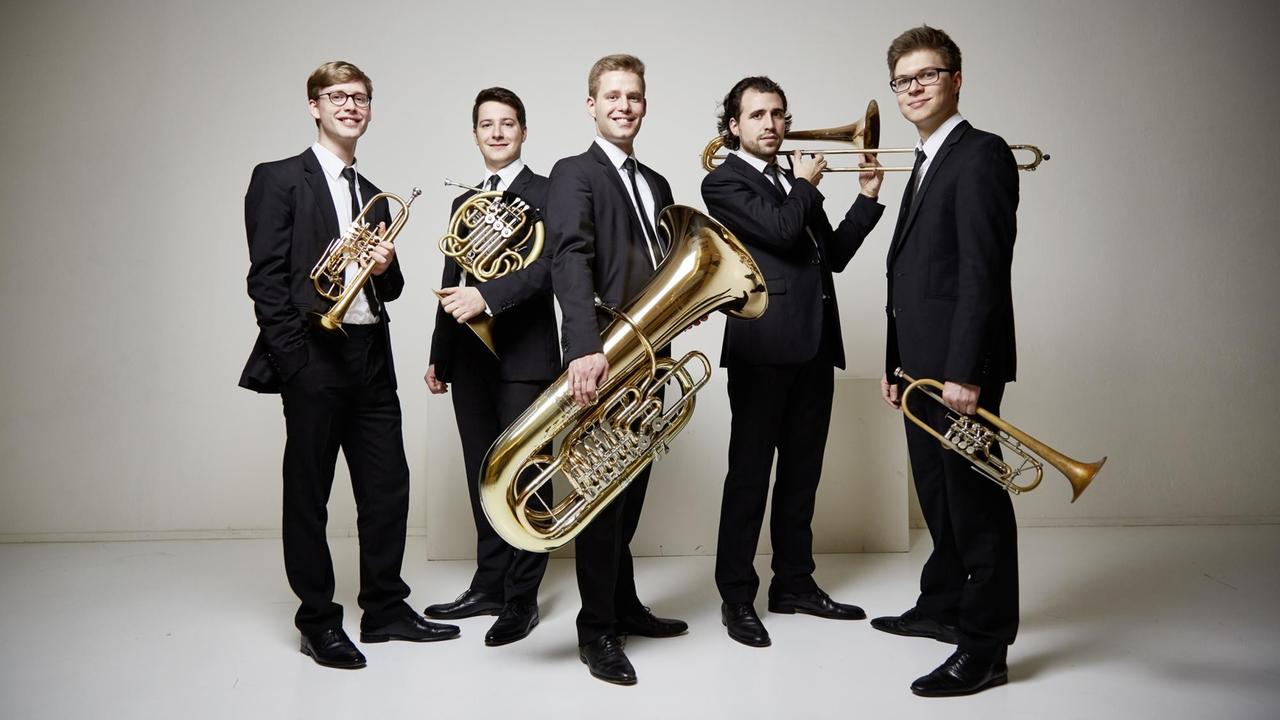 Die Fünf Musiker stehen festlich gekleidet mit ihren Instrumenten in einer Gruppe.