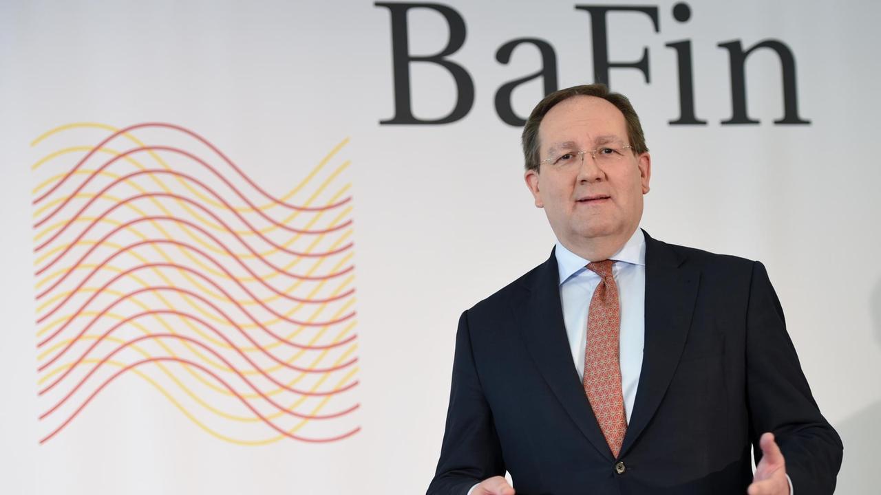 Felix Hufeld, Präsident der BaFin steht vor einem Logo der Bundesanstalt.