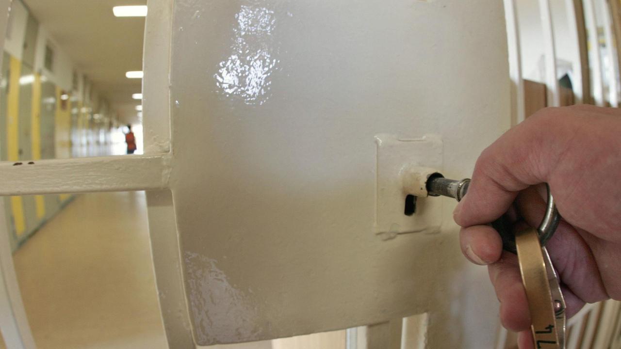 Ein Beamter verschliesst eine Tür in einem Gefängnistrakt der Justizvollzugsanstalt