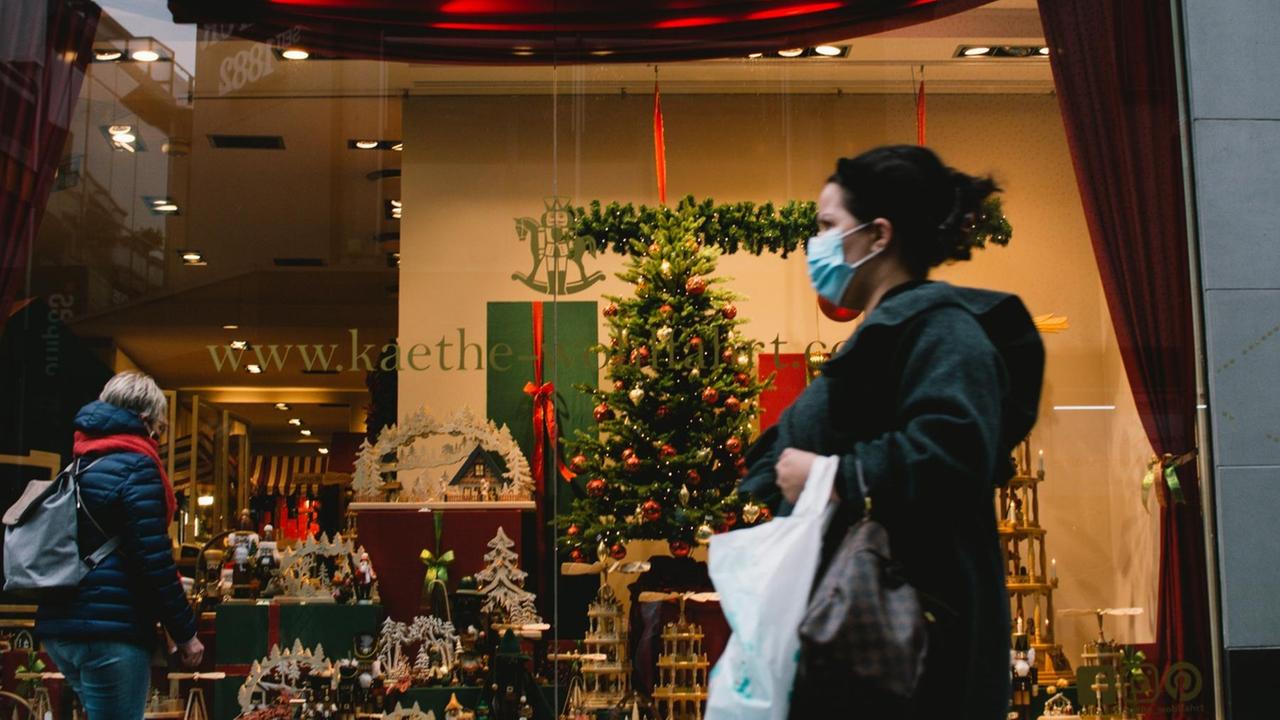 Eine Frau mit Mund-Nasen-Maske läuft ini Köln an einem Laden mit Weihnachtsdekoration vorbei.  (Photo by Ying Tang/NurPhoto) | Keine Weitergabe an Wiederverkäufer.