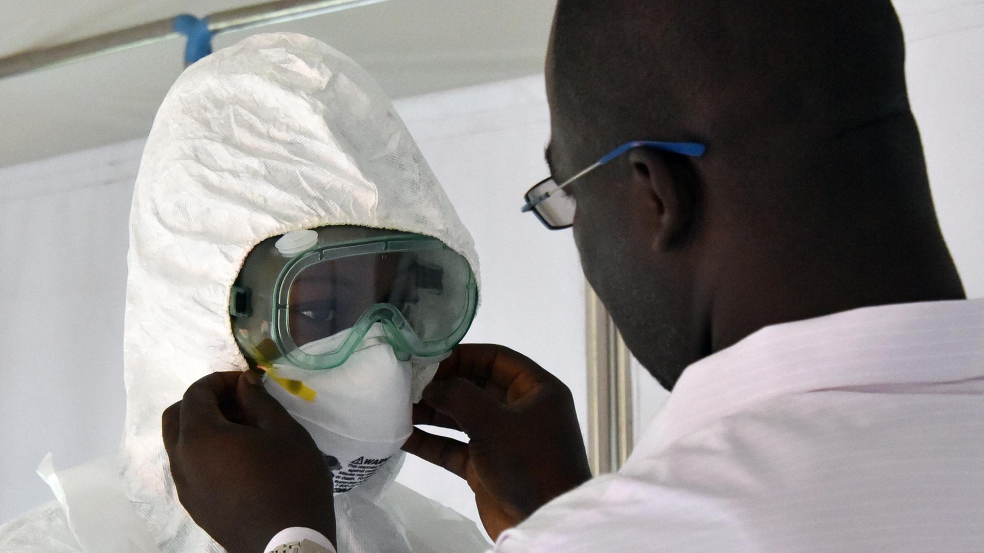 Ein afrikanischer Arzt hilft seinem Kollegen, dessen Atemschutzmaske anzupassen.