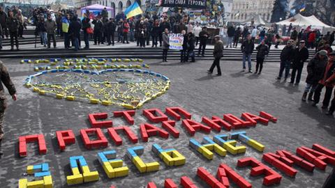 Auf dem Boden steht aus roten, blauen und gelben Bauklötzen groß ein Satz auf dem Boden: "Stoppt Propaganda! Es gibt hier keinen Faschismus".