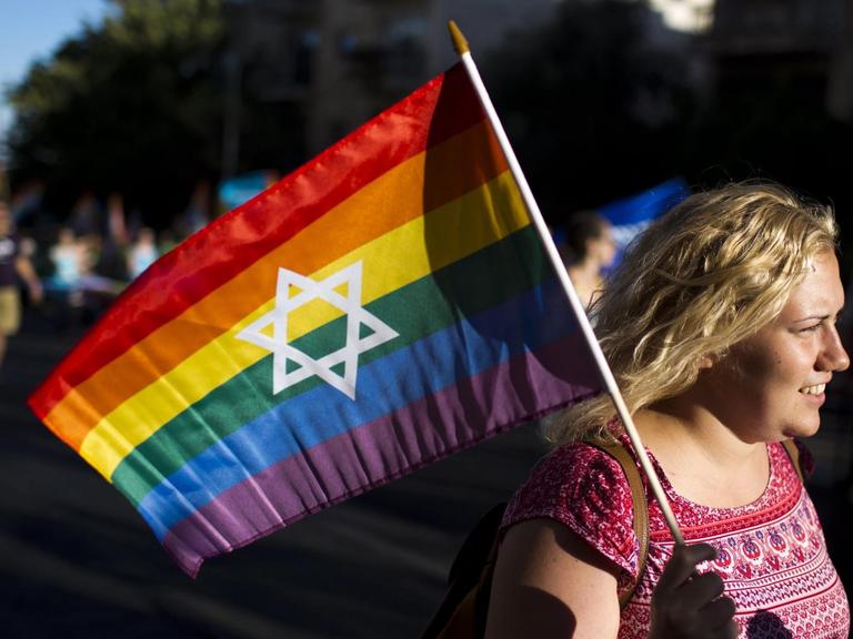 Eine Frau hält während einer Gay-Pride-Parade in Jerusalem 2016 eine Regenbogenfahne mit einem Davidstern in der Mitte in der Hand.