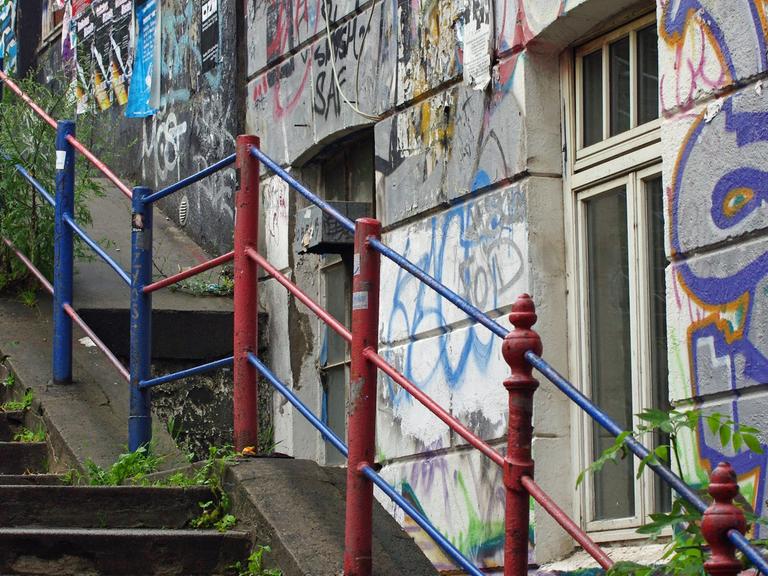 Ein Haus mit Graffitis an einer Treppe mit buntem Geländer